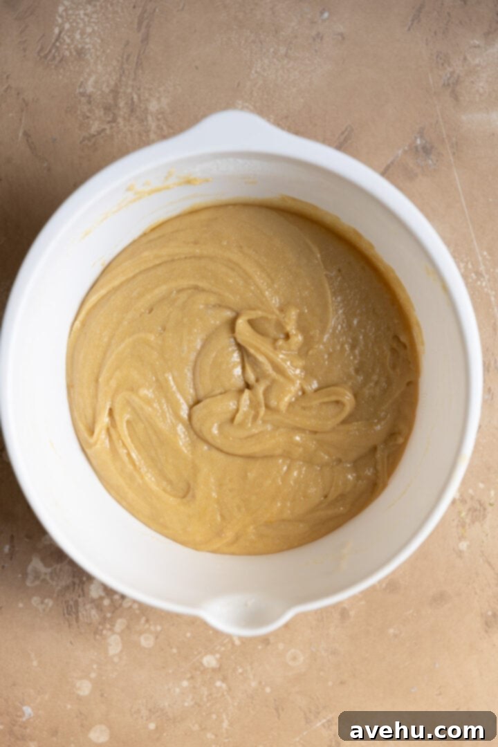 A smooth, light-colored cookie batter fills a white mixing bowl, showcasing the perfect consistency before dividing.
