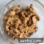 Effortless Chewy Brookie Bliss 5 Chocolate chip cookie dough, thick and full of chips, in a glass mixing bowl.