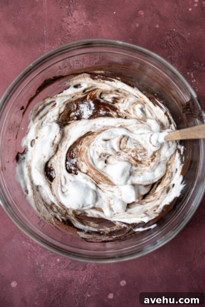 Velvet Chocolate Mousse Cake No Gelatin Needed 10 Egg whites being folded into chocolate in a bowl.