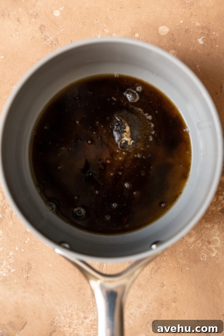 Silky Smooth Cookie Dough Frosting 4 Close-up of brown sugar and water combined in a small saucepan, heating on a stovetop.
