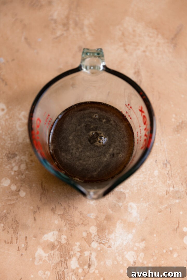 Silky Smooth Cookie Dough Frosting 5 Rich brown sugar syrup poured into a clear measuring cup, showing its smooth, glossy consistency.