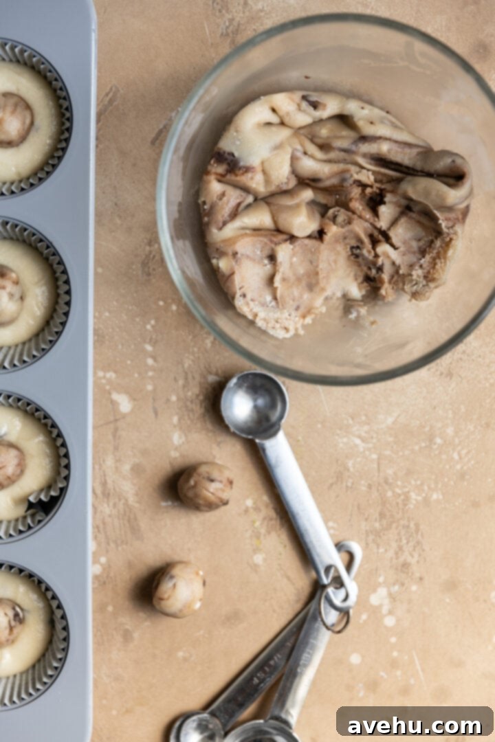 Easy Surprise Cookie Dough Cupcakes 9 A bowl of cookie dough next to a teaspoon and small cookie dough balls.