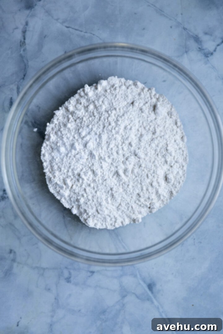 Effortlessly Moist Pineapple Cupcakes 4 Dry ingredients for cupcakes in a bowl on a blue surface.