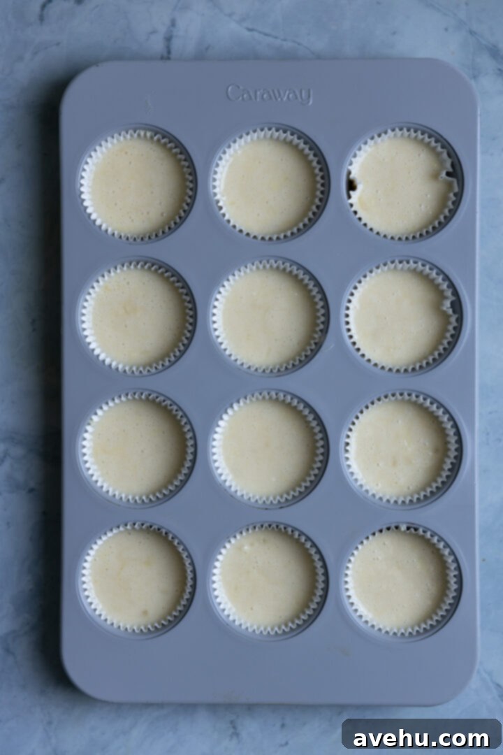 Effortlessly Moist Pineapple Cupcakes 7 Cupcake batter in a gray muffin tin.