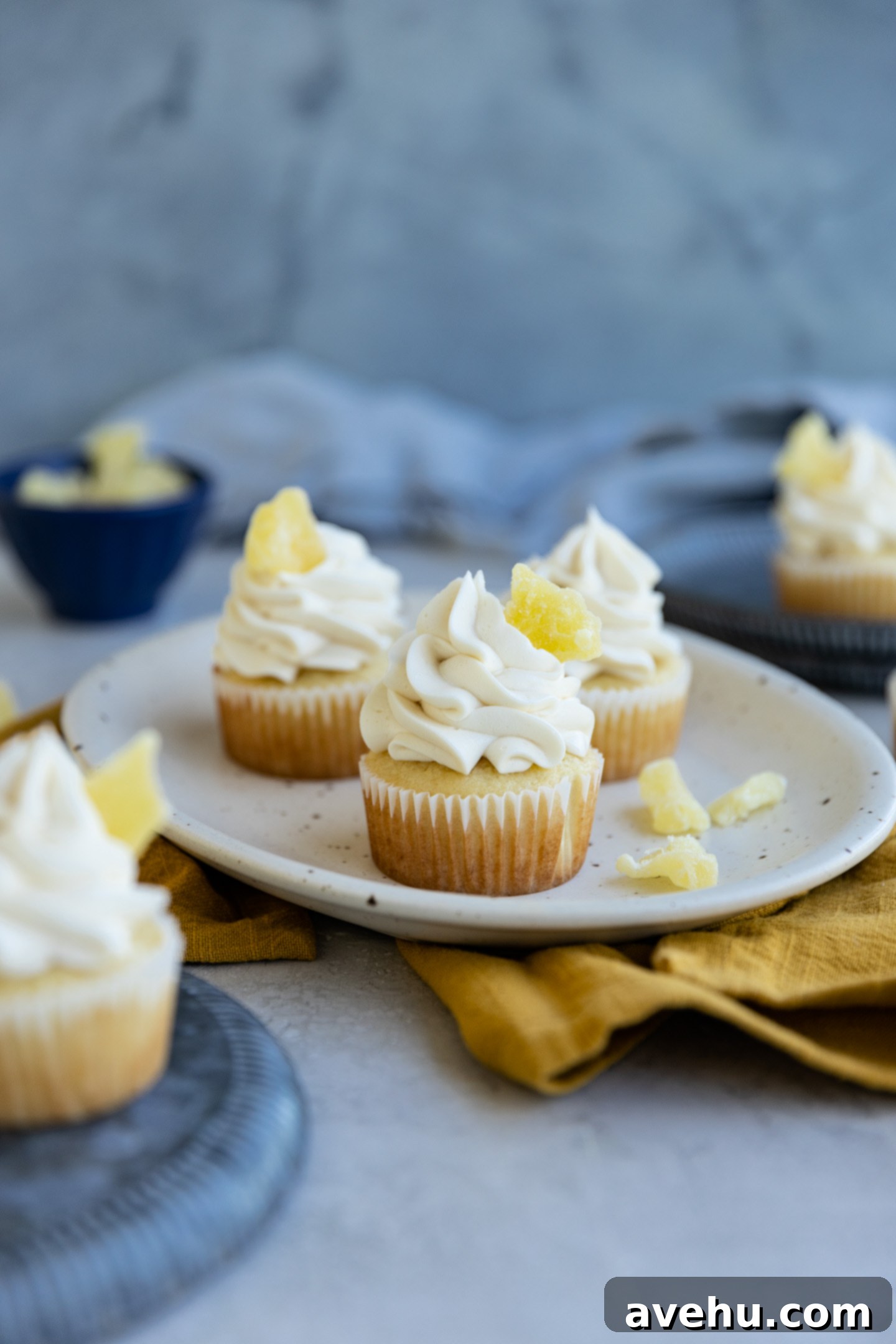 Effortlessly Moist Pineapple Cupcakes 8 Three pineapple cupcakes on a small platter on top of a yellow napkin.