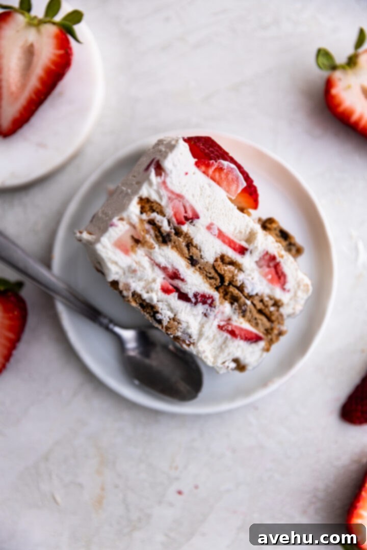 Chilled Strawberry Cloud Cake 11 A pristine slice of strawberry icebox cake, showing distinct layers of whipped cream, cookies, and strawberries, served on a small white plate.