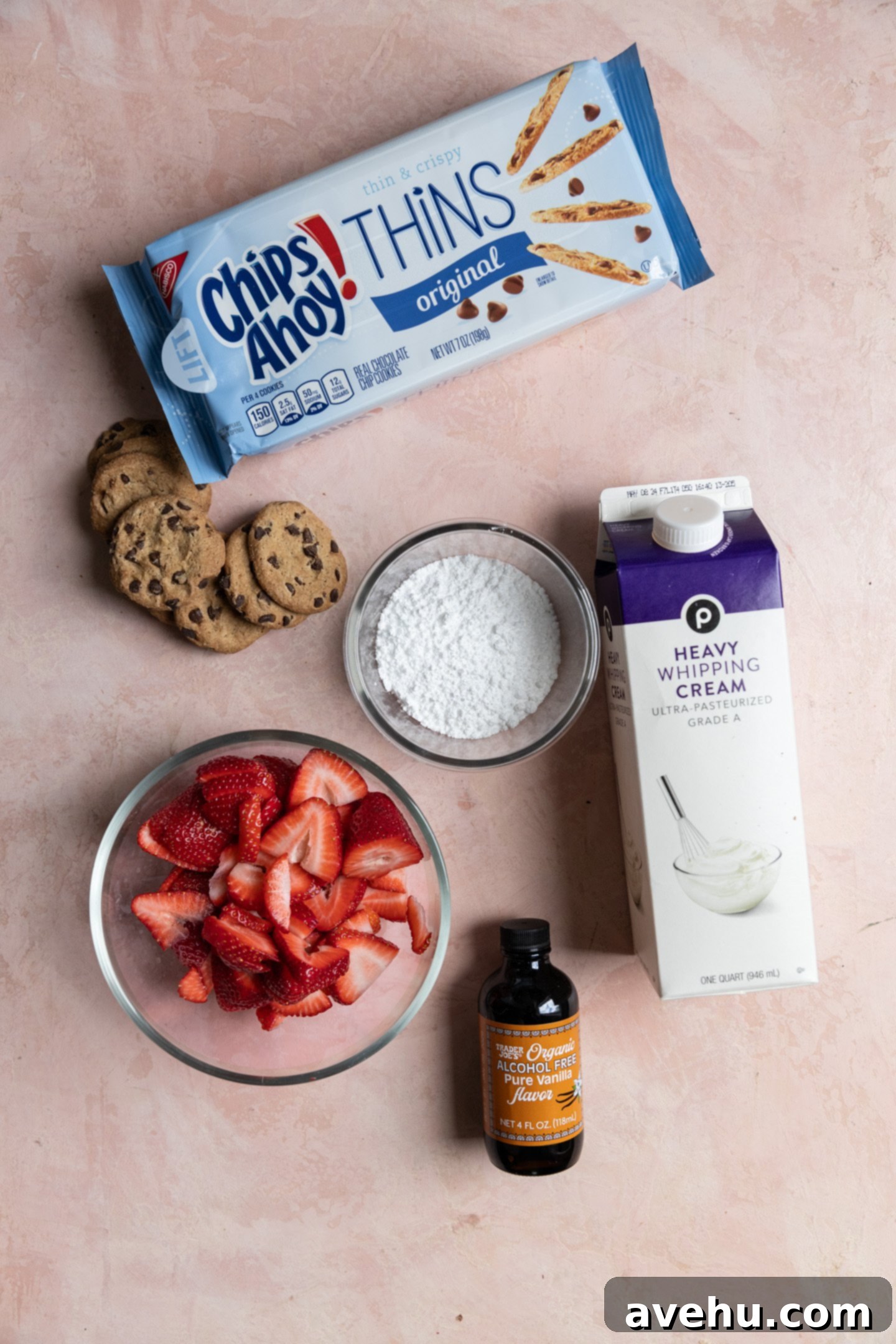 Chilled Strawberry Cloud Cake 3 A flat lay photograph showcasing the five simple ingredients required for the strawberry icebox cake: fresh strawberries, thin chocolate chip cookies, heavy whipping cream, powdered sugar, and vanilla extract.
