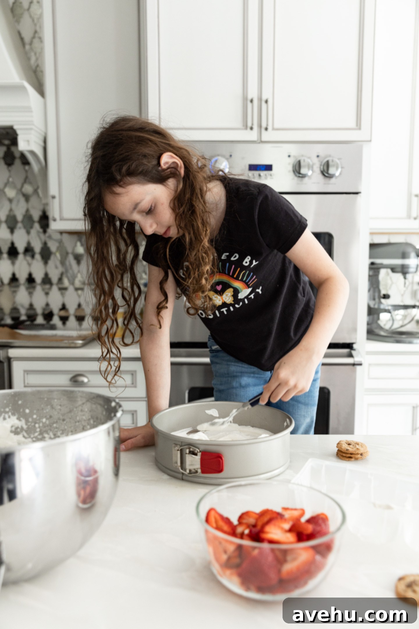 Chilled Strawberry Cloud Cake 4 A child carefully spreading a layer of whipped cream into a round springform pan, part of the strawberry icebox cake assembly process.