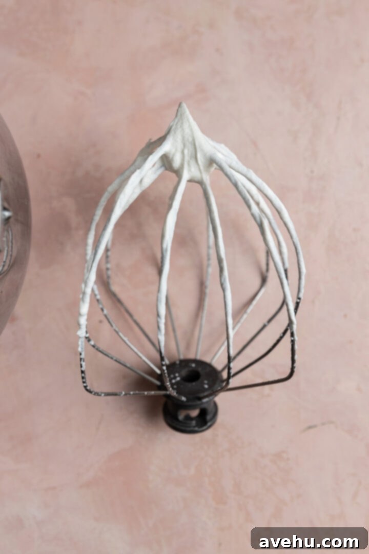 Chilled Strawberry Cloud Cake 5 A whisk attachment showing perfectly stiff peaks of freshly whipped cream, indicating it's ready for layering in the icebox cake.