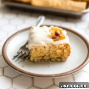 Tropical Pineapple Cake, Cream Cheese Crowned 8 A piece of pineapple cake with cream cheese frosting on a brown rimmed white plate.