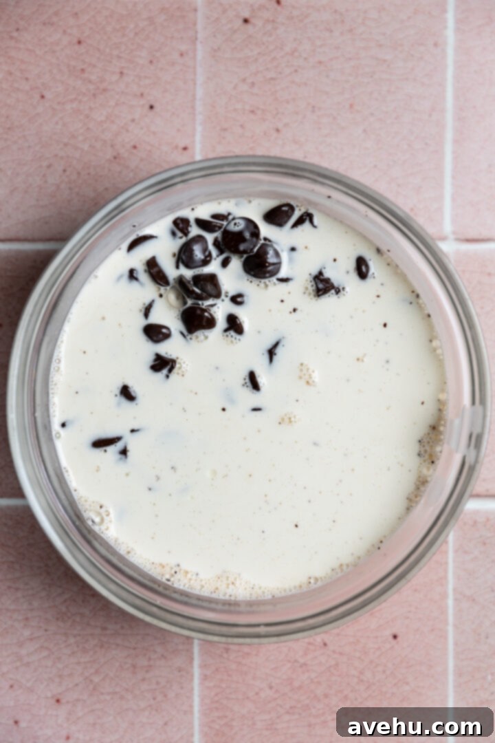 Foolproof S'mores Pie with Decadent Chocolate 6 Cream poured over chocolate chips in a bowl.