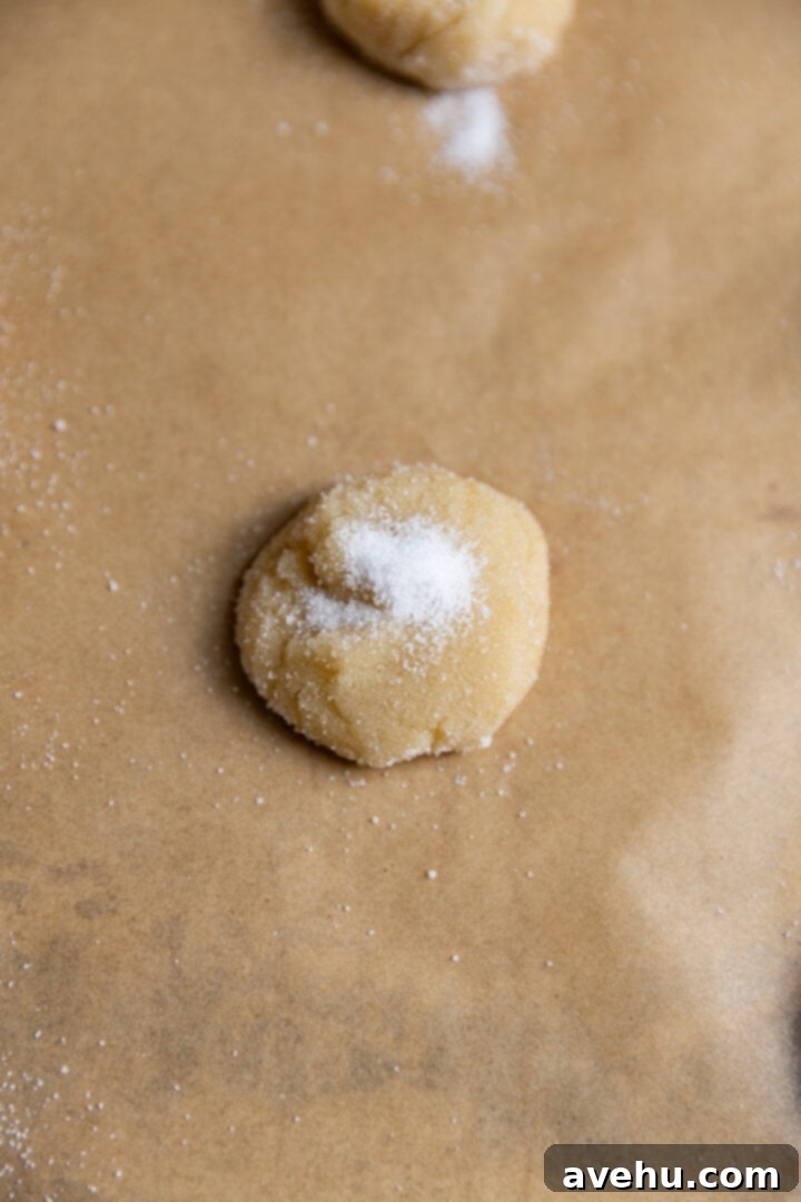 20-Minute Mixer-Free Sugar Cookies 7 A perfectly shaped sugar cookie dough ball, evenly coated in granulated sugar, on parchment paper.