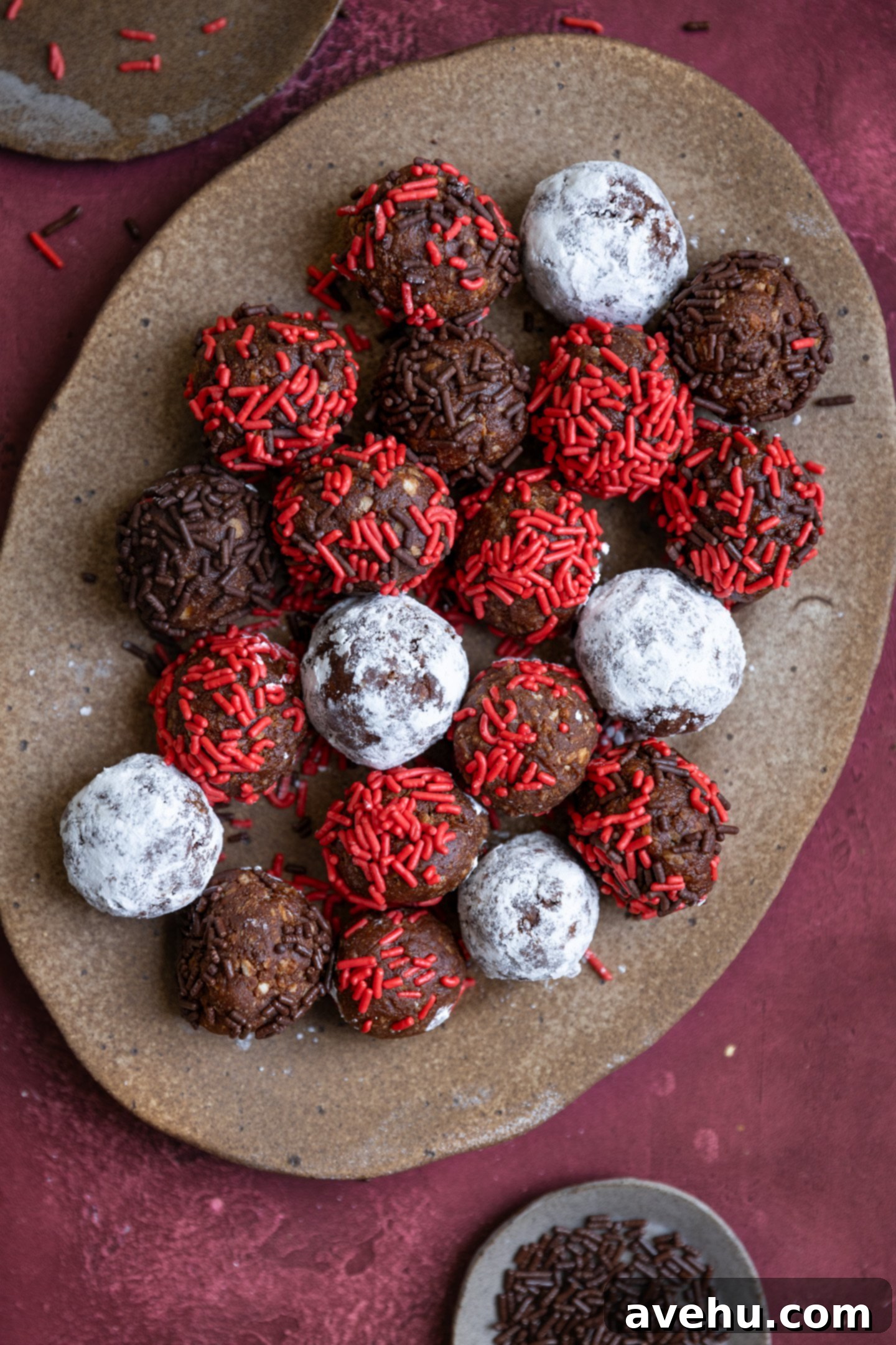 20-Minute Boozy Festive Rum Ball Recipe 2 Rum balls with different festive toppings on a rustic brown platter, ready for holiday celebrations.