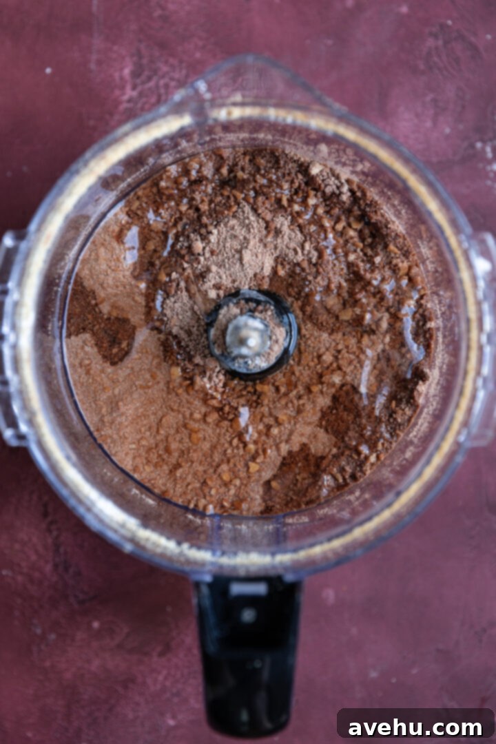 20-Minute Boozy Festive Rum Ball Recipe 7 Wet ingredients (corn syrup and rum) being added to the dry mixture in a food processor.