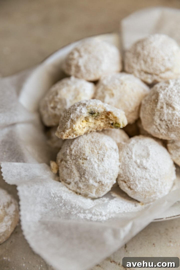 Effortless 3-Ingredient Snowball Cookies 11 A snowball cookie with a bite taken out on a stack of other cookies.
