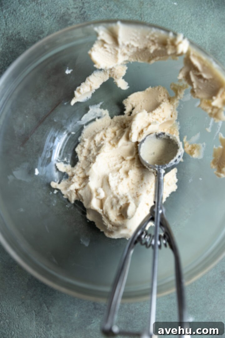 Effortless 3-Ingredient Snowball Cookies 8 A small cookie scoop in the bowl of snowball cookie dough.