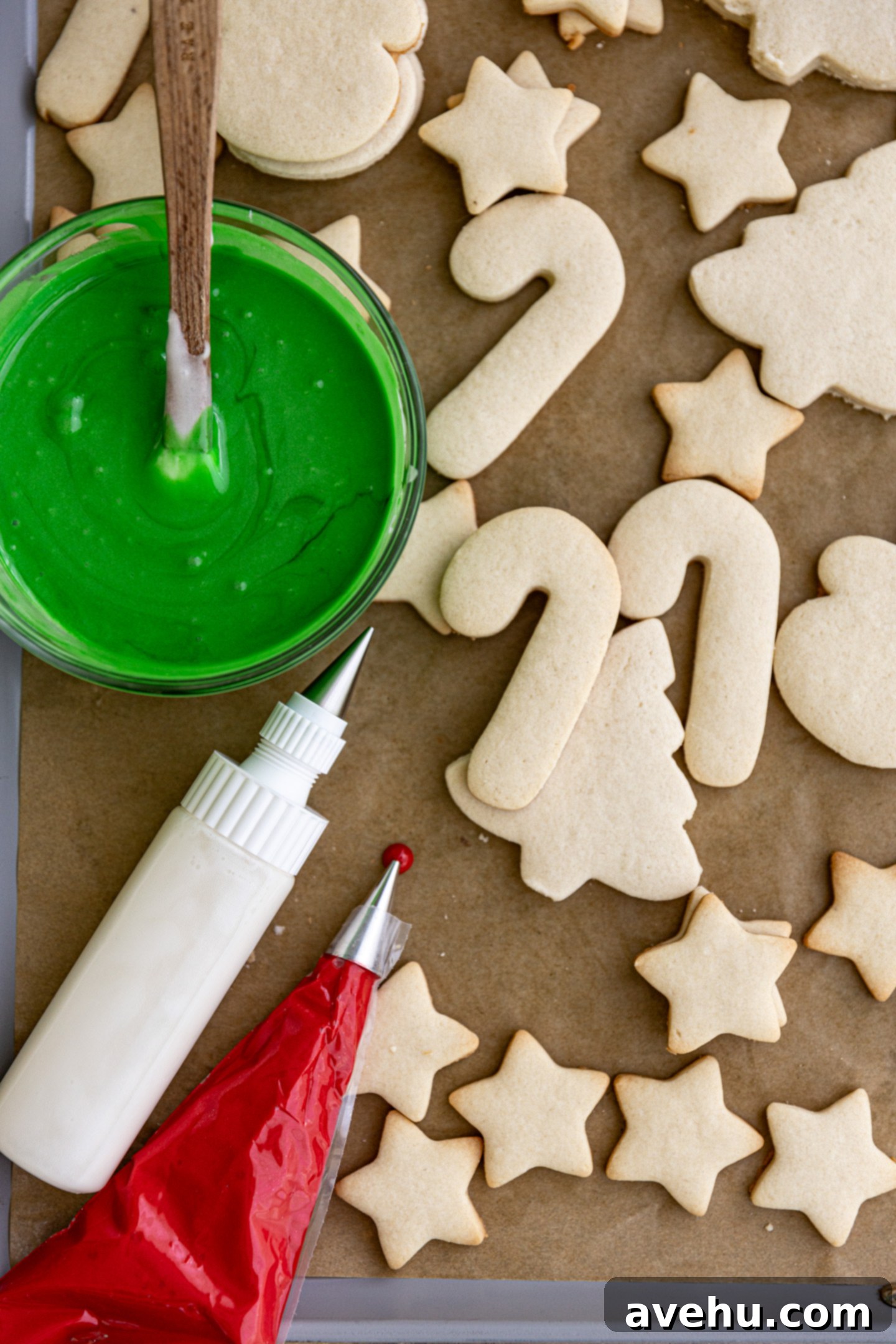 Instant Cut-Out Sugar Cookies 11 Uniced cut-out sugar cookies arranged next to a bowl of royal icing, a piping bag, and a squeeze bottle, ready for decoration.