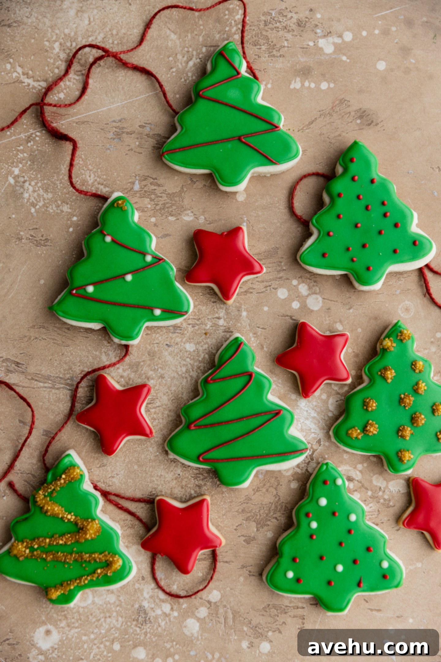 Quick Royal Icing Without Meringue Powder 2 Christmas tree and star cookies iced with green and red royal icing on a beige background.
