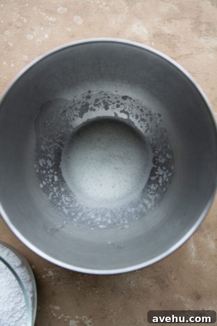 Quick Royal Icing Without Meringue Powder 4 Egg whites foaming in a mixing bowl.