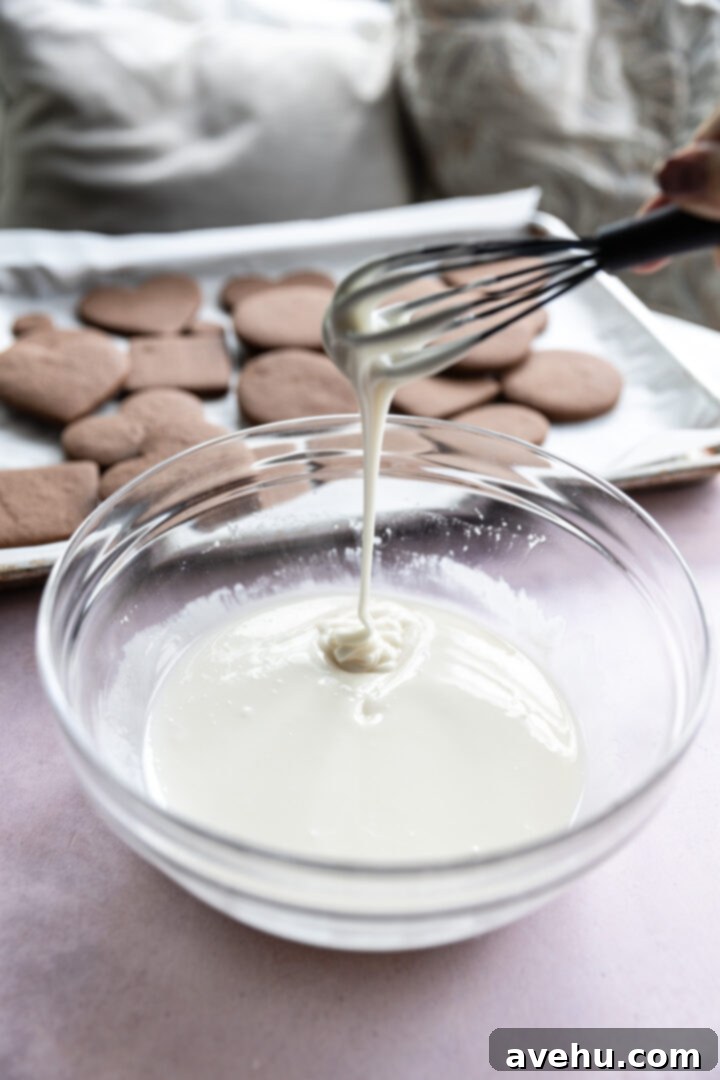Quick No-Piping Cookie Icing 5 Cookie icing drizzling off a whisk with cookies in the background.