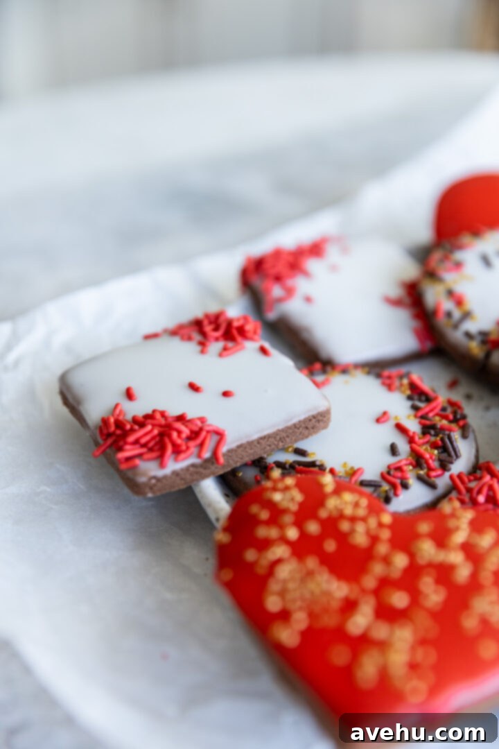 Quick No-Piping Cookie Icing 10 Cookies with icing and sprinkles on parchment paper.