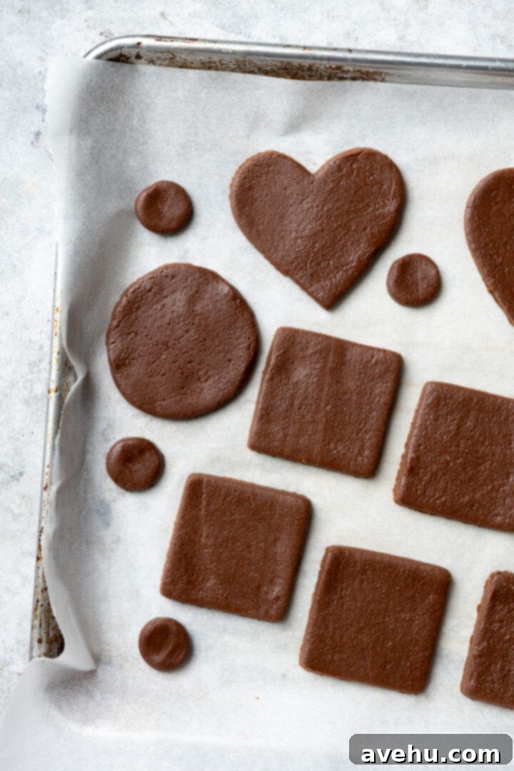 Instant Chocolate Sugar Cookie Delight 10 Multiple chocolate cookie shapes, perfectly cut, arranged closely on parchment paper on a baking sheet, ready for the oven.