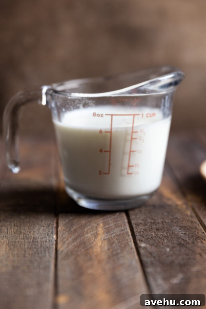 Instant Comfort Microwave Hot Cocoa for One 4 A microwave-safe glass measuring cup, filled with fresh milk, sits on a rustic wooden surface, poised to be heated for the hot chocolate recipe.