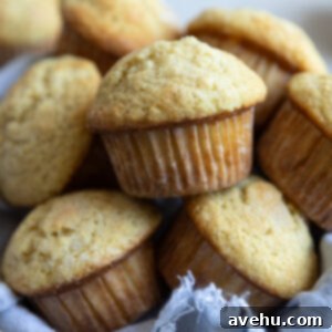 Classic Soft & Moist Muffins 9 Muffins on top of each other in a bowl lined with a blue linen.