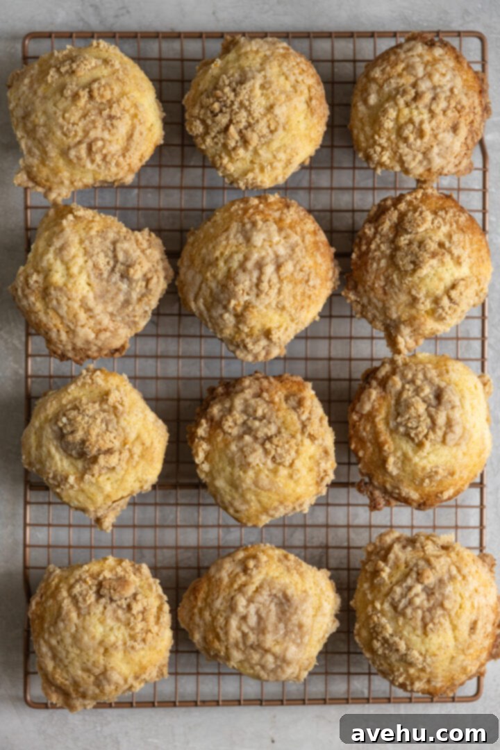 Gourmet Triple Lemon Muffins 11 Freshly baked lemon muffins with golden streusel tops, some gently touching in the muffin tin, showcasing their tall domes.