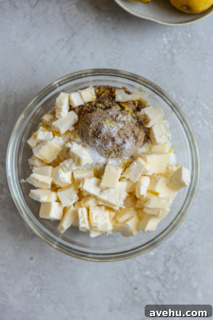 Gourmet Triple Lemon Muffins 3 Ingredients for lemon streusel are mixed in a clear glass bowl, showing cold butter pieces ready to be incorporated.