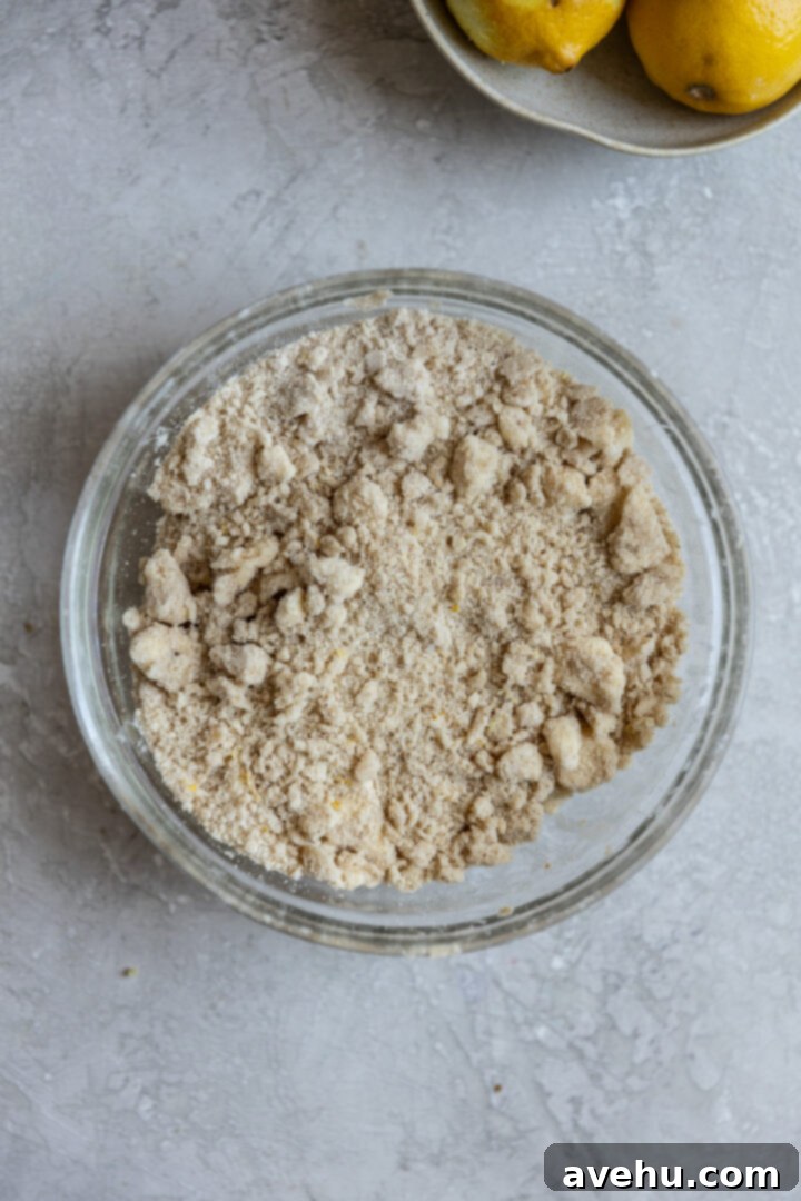 Gourmet Triple Lemon Muffins 4 Finished lemon streusel in a bowl on a gray surface, showing small, distinct clumps ready for topping muffins.