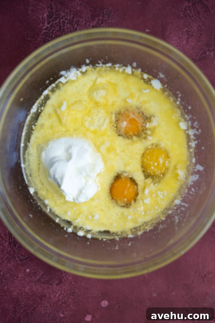 Luminous Lemon Raspberry Muffins 5 Wet ingredients for lemon raspberry muffins, including melted butter, oil, milk, eggs, Greek yogurt, and lemon extract, in a glass bowl.