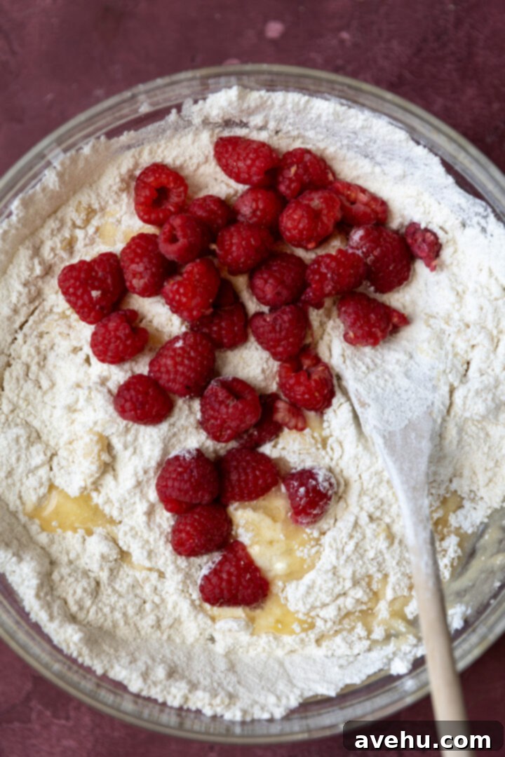 Luminous Lemon Raspberry Muffins 6 Fresh raspberries resting on top of lemon muffin batter in a mixing bowl, ready to be folded in.