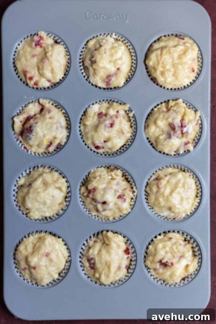 Luminous Lemon Raspberry Muffins 8 Lemon raspberry muffin batter neatly scooped into a muffin tin, filling each cup to the brim.