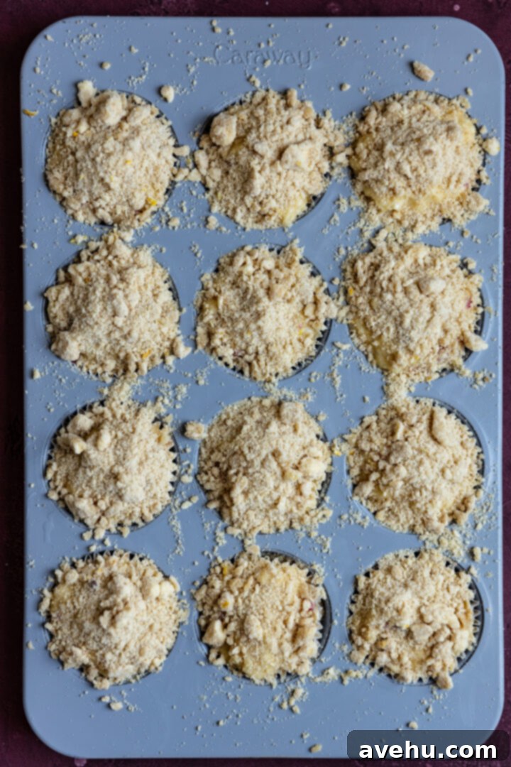 Luminous Lemon Raspberry Muffins 9 Muffin batter in a tin, generously topped with lemon streusel, ready for baking.