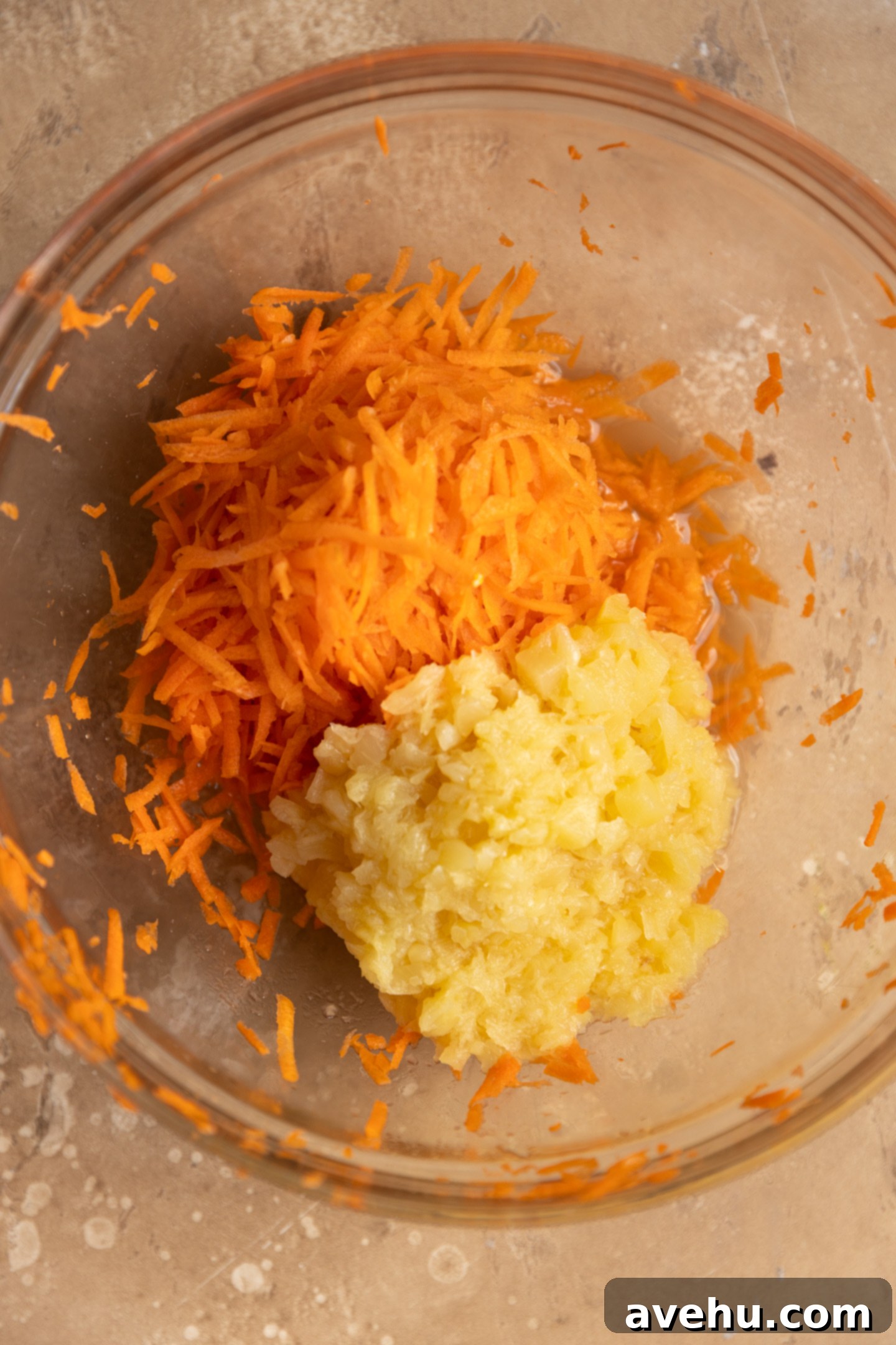 Kid-Approved Carrot Pineapple Muffins 3 Freshly hand-shredded carrots and perfectly portioned crushed pineapple in a clear glass bowl, ready for mixing.