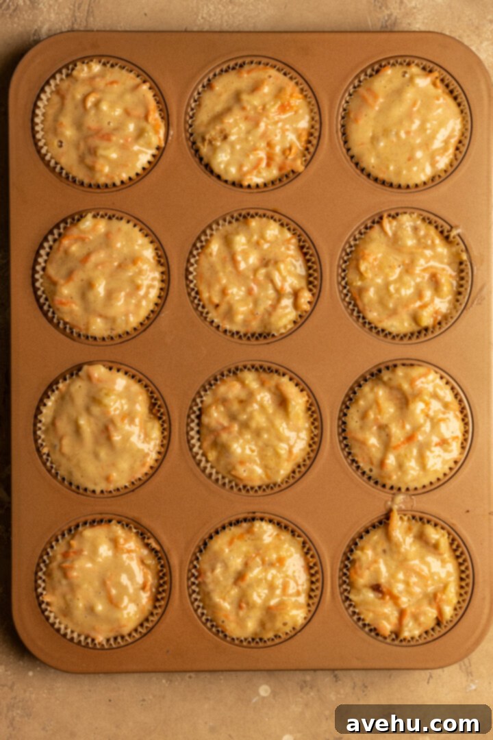 Kid-Approved Carrot Pineapple Muffins 7 Muffin batter generously filled to the top of a muffin tin, preparing for baking to achieve impressive bakery-style domes.