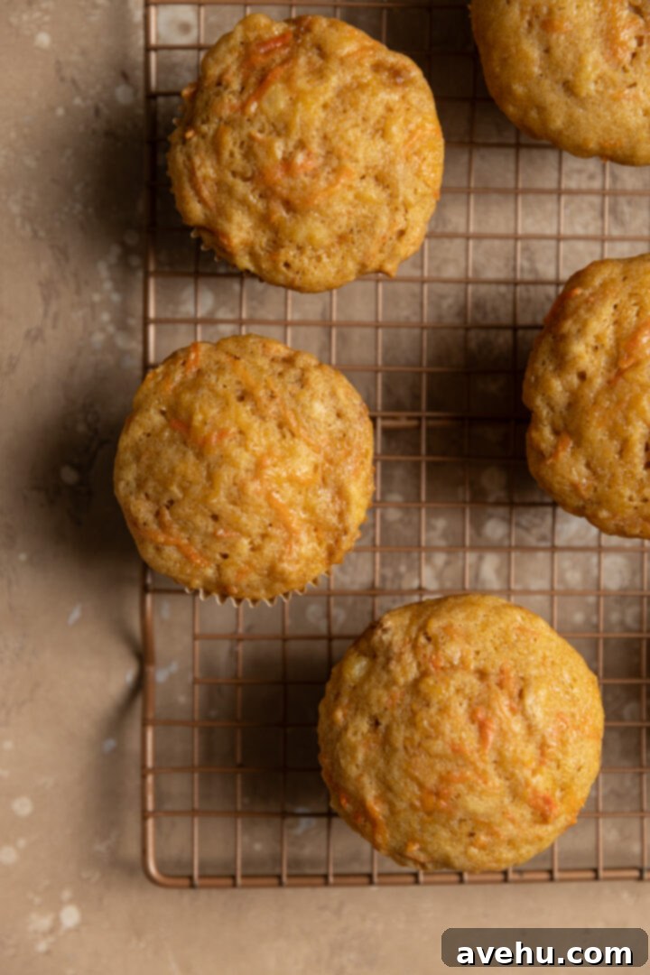 Kid-Approved Carrot Pineapple Muffins 8 Freshly baked carrot pineapple muffins cooling on a wire rack after being removed from the tin.