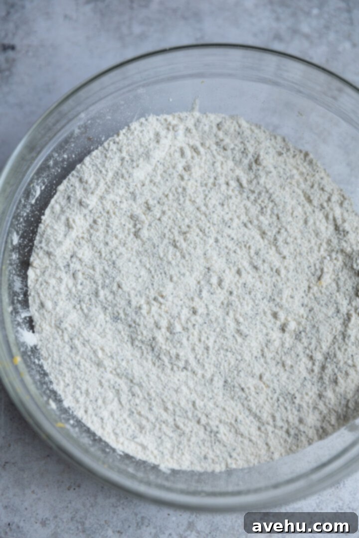 Lemon Poppy Seed Muffins Beyond Bakery Quality 4 A pristine white mixing bowl filled with dry ingredients for lemon poppy seed muffins, ready to be combined.