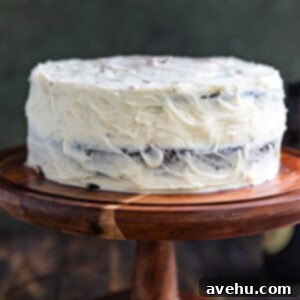 Guinness Kissed Chocolate Cake with Baileys Cloud 11 A Guinness chocolate cake with white frosting on a wooden cake stand, ready to be sliced.