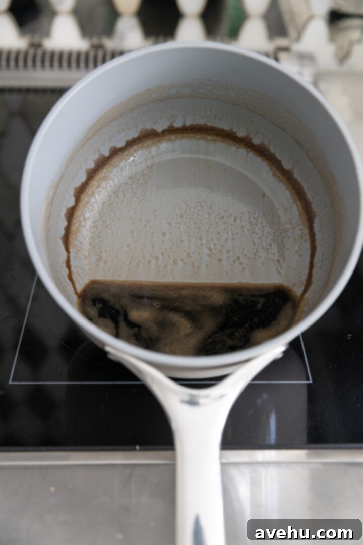 Guinness Kissed Chocolate Cake with Baileys Cloud 7 Dark, syrupy reduced Guinness in a pot on the stove, showcasing its concentrated flavor.