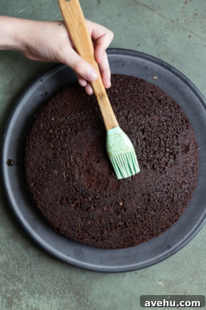 Guinness Kissed Chocolate Cake with Baileys Cloud 8 A pastry brush applying the syrupy Guinness reduction onto a baked chocolate cake layer.