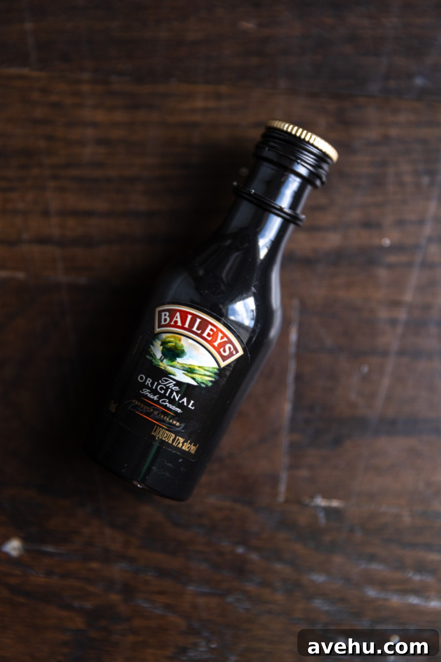 5 Minute Spiked Baileys Frosting 5 A small bottle of Baileys Irish Cream resting on a rustic wooden surface.