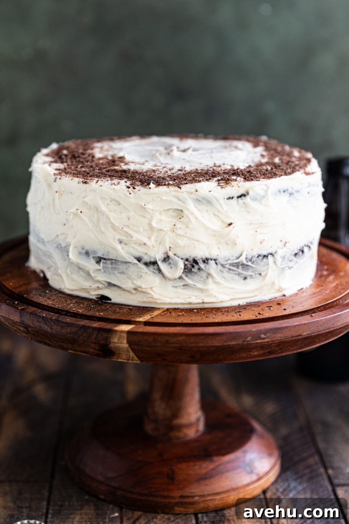 5 Minute Spiked Baileys Frosting 6 A beautifully frosted chocolate cake with Baileys frosting and chocolate shavings on a wooden cake stand.