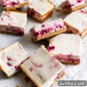 Effortless Cranberry Cheesecake Bars 2 Cranberry cheesecake bars on parchment paper.