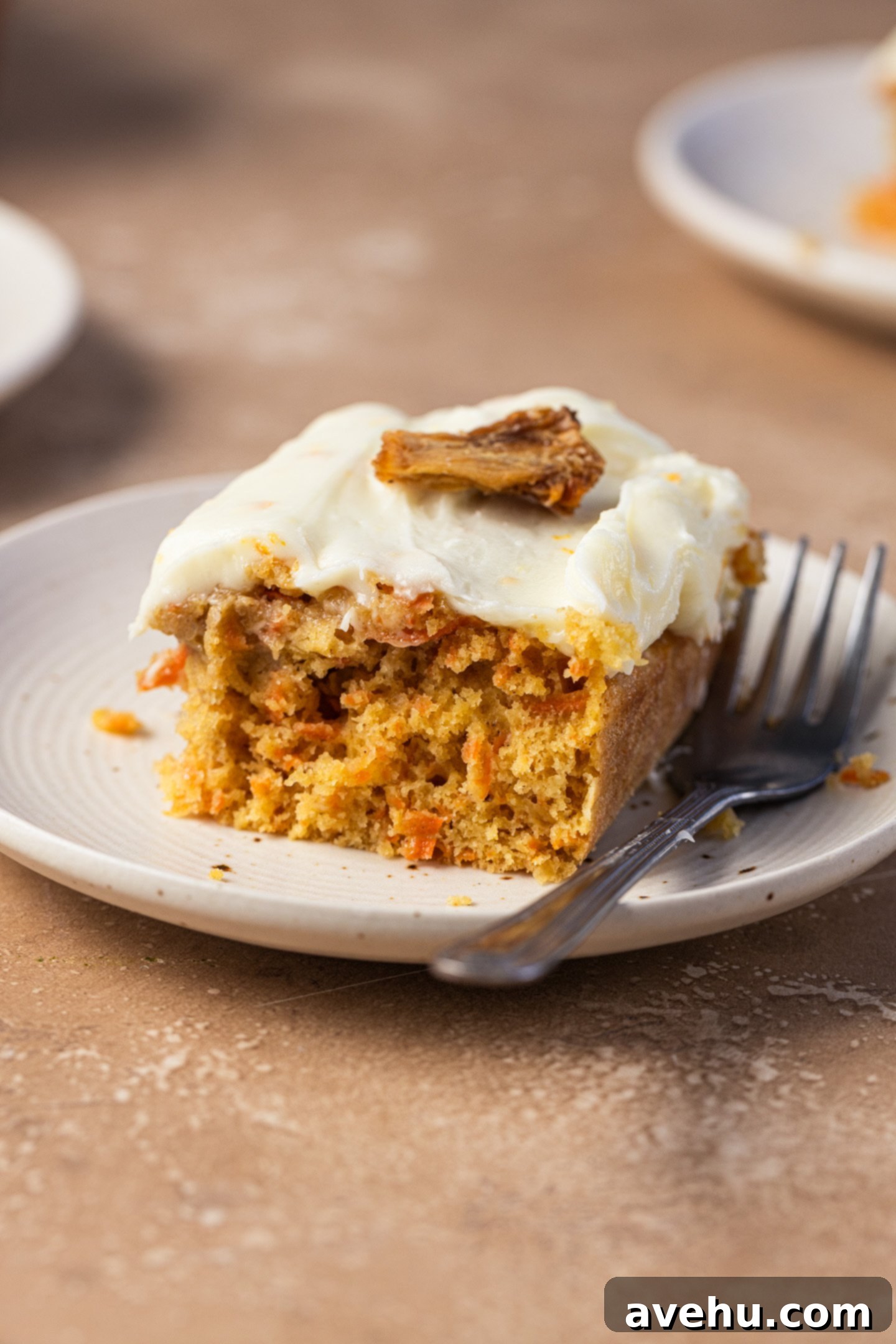 Sunshine Carrot Pineapple Sheet Cake 2 A piece of a carrot pineapple cake on a small plate next to a fork.