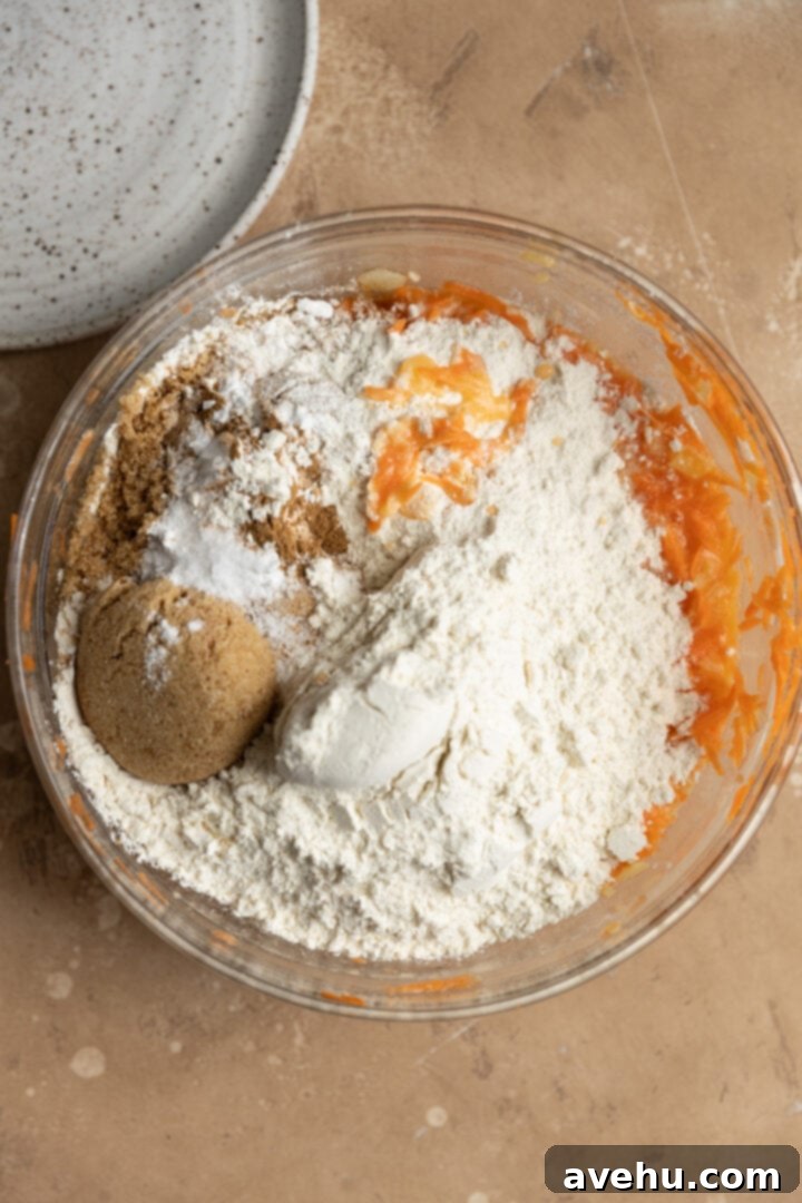 Sunshine Carrot Pineapple Sheet Cake 5 Dry ingredients added to a wet batter in a glass bowl.