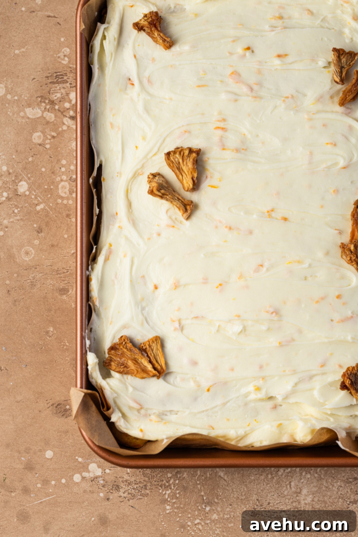 Sunshine Carrot Pineapple Sheet Cake 7 A sheet cake topped with cream cheese frosting and garnished with dried pineapple.