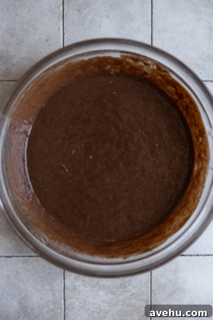 Melt-in-Your-Mouth S'mores Chocolate Muffins 5 Wet ingredients for S'mores muffins, including melted butter and chocolate, milk, yogurt, eggs, and vanilla, in a bowl.