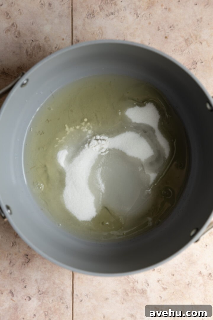 Effortless 7-Minute Frosting 4 Ingredients for 7 minute frosting, including egg whites, sugar, cream of tartar, and water, in a large pot.